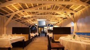 Un restaurant doté d’un plafond voûté très haut et de tables dressées pour le service.