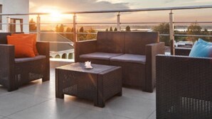Une terrasse sur le toit, aménagée avec des meubles en osier, offrant une vue sur le coucher de soleil.