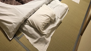 Two beds with white sheets and brown blankets, a small table with a bottle, and a window with curtains. - Condominium Seafront Moon and Sand (Ito)