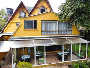 A yellow house with a large glass windowed patio area.