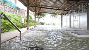 A hot spring area with a covered walkway and a metal railing. - Wan Jin Hot Spring (New Taipei City)