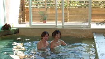 Una piccola piscina interna con un pontile in legno e una finestra vista su del verde.