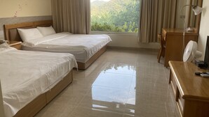 A hotel room with two beds, a wooden desk, a mirror, and a view of greenery outside. - Wan Jin Hot Spring (New Taipei City)