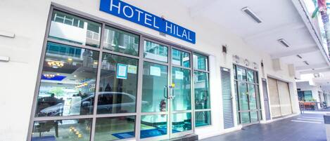 Ein moderner Hotelzugang mit einer großen Glasfassade, einem blauen Schild mit der Aufschrift "HOTEL HIMAL" und einem gefliesten Boden.