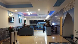 A hotel lobby with a reception desk, seating area, and a large bed. - Hotel Hilal (Cyberjaya)