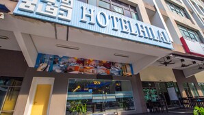 A hotel with a prominent sign, large windows, and a seating area outside. - Hotel Hilal (Cyberjaya)