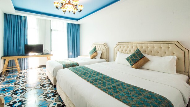 A hotel room with two beds, a TV on a desk, and a chandelier. - Hotel Hilal (Cyberjaya)