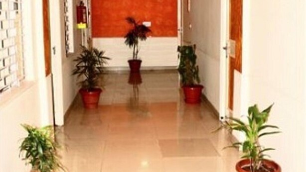 A hallway with a ceiling fan, red walls, and potted plants. - Accent Hotel (Greater Noida)