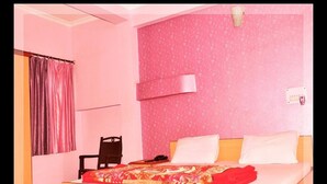 A bedroom with a bed, a chair, a desk, and a curtain. - Accent Hotel (Greater Noida)