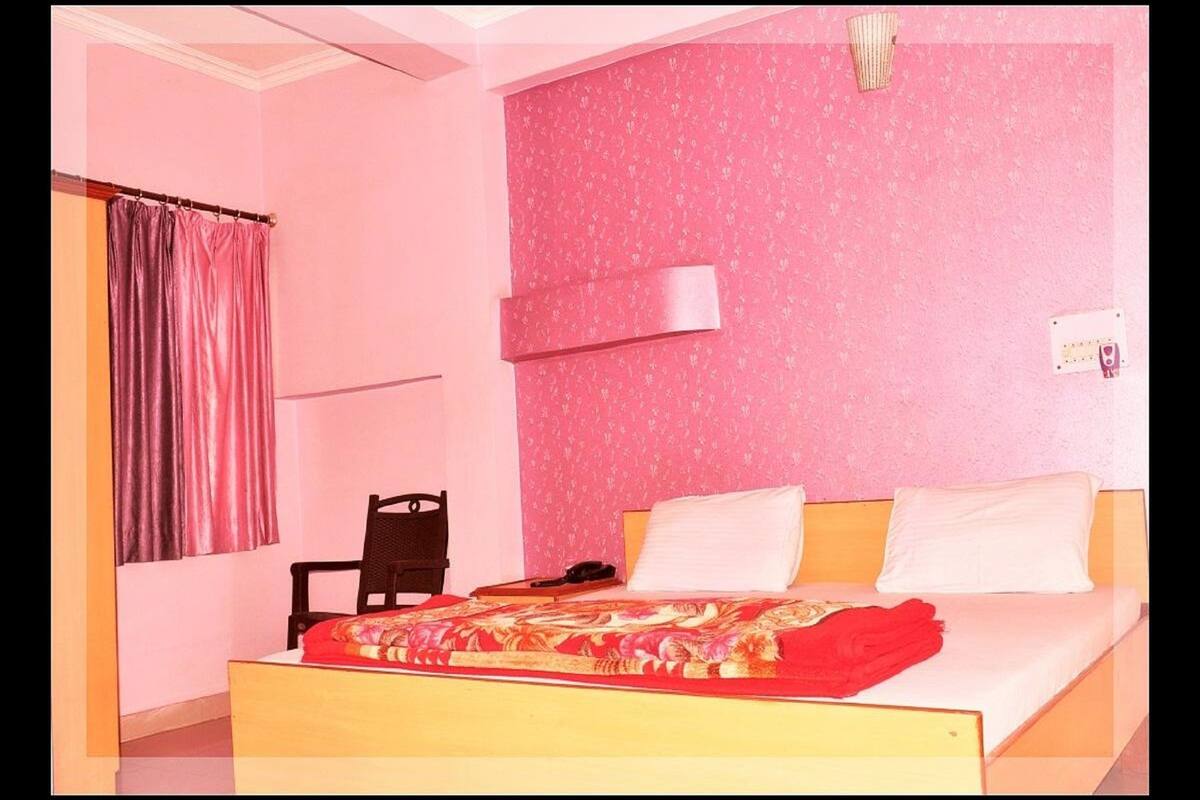 A bedroom with a bed, a chair, a desk, and a curtain.