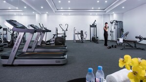 Uma academia com esteiras, aparelhos de musculação e uma pessoa se exercitando.