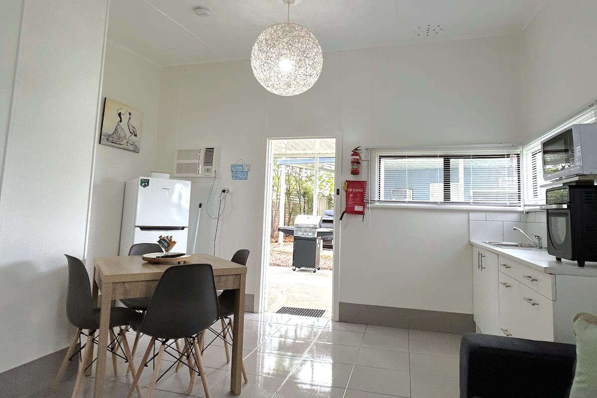 A compact kitchen with a dining area, a ceiling light fixture, and a fire extinguisher on the wall.