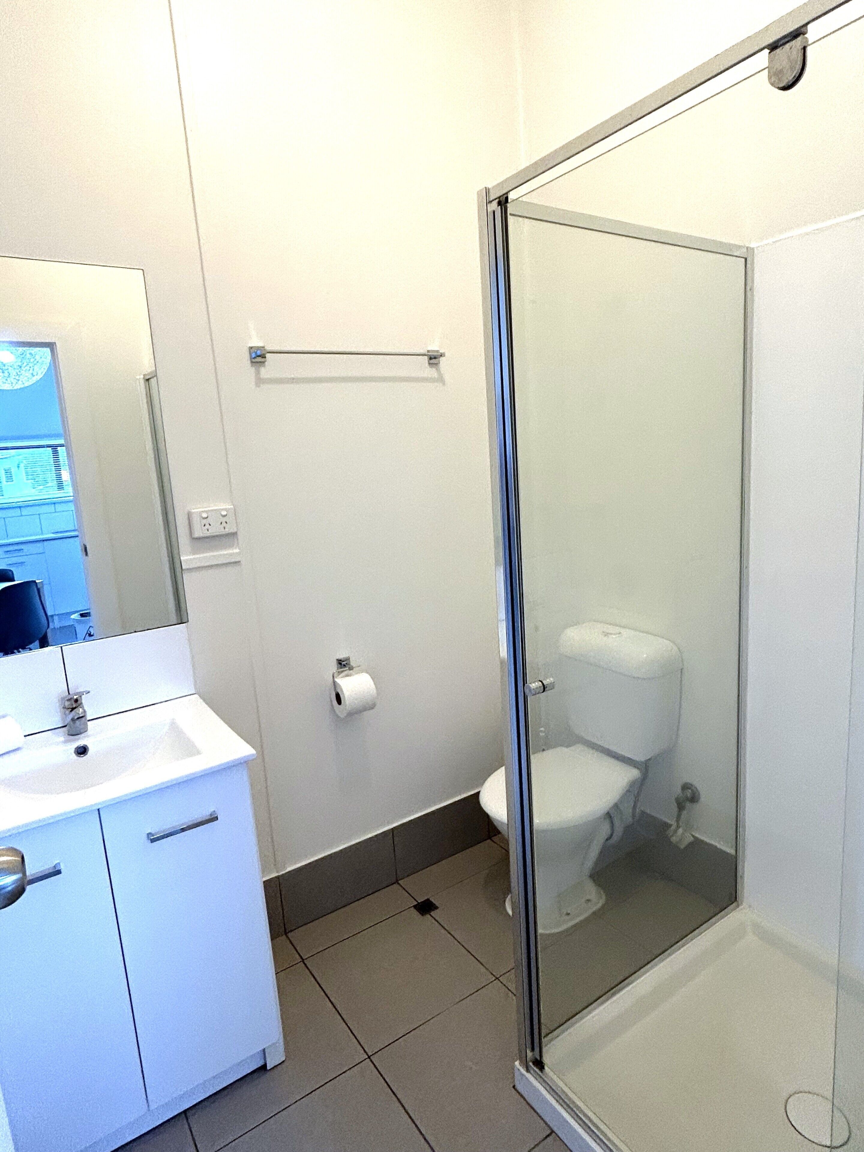 A bathroom with a glass-enclosed shower, a white sink, and a toilet.