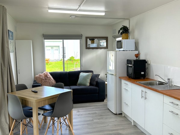 Una cocina compacta con comedor, refrigerador, microondas y pileta.