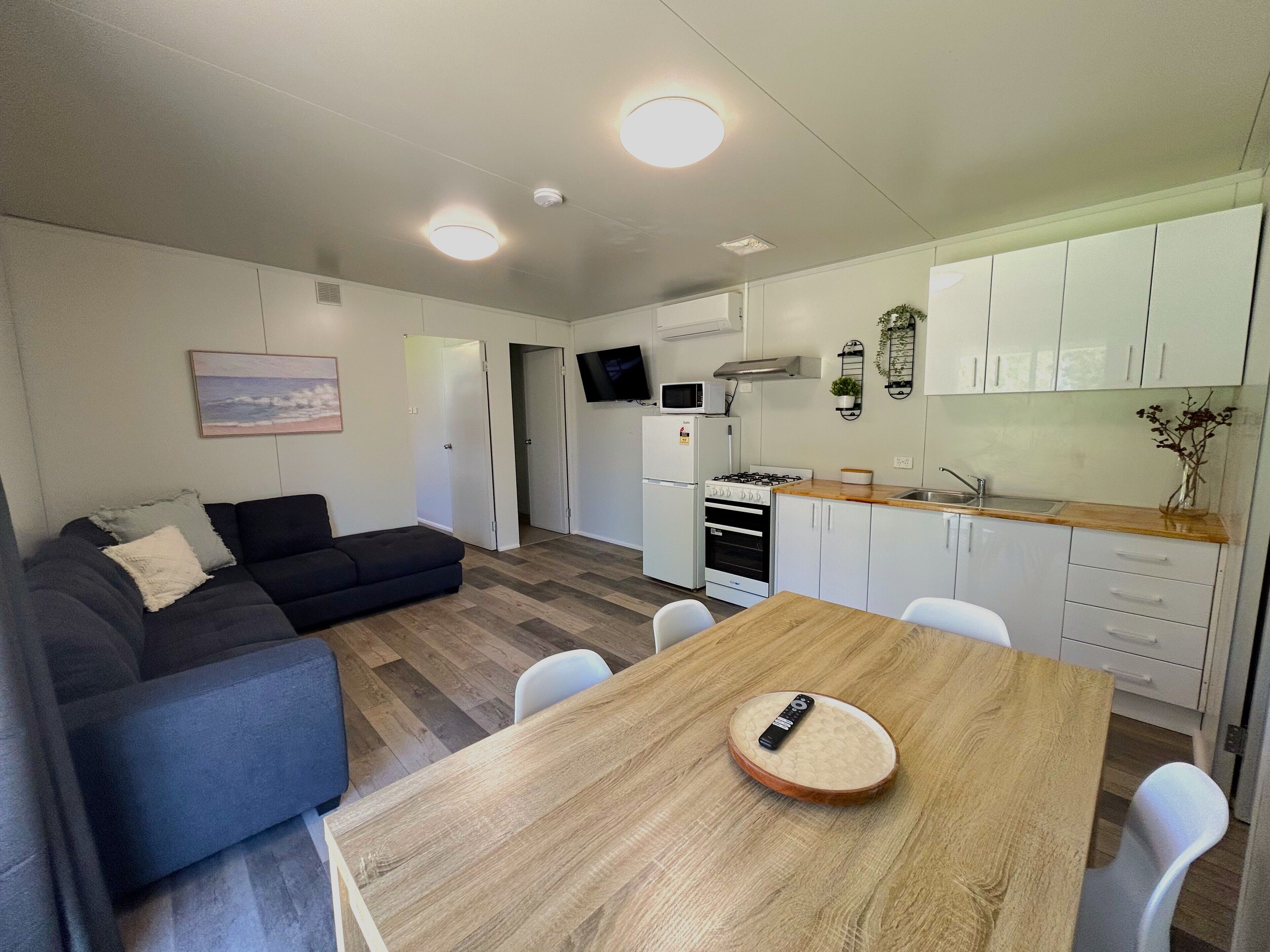 A compact living space with a dining area, kitchenette, and a gray sofa.