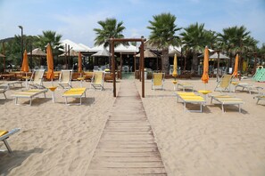 A beach with wooden walkways, yellow sun loungers, and orange umbrellas. - Camping Euro 92 (Vieste)