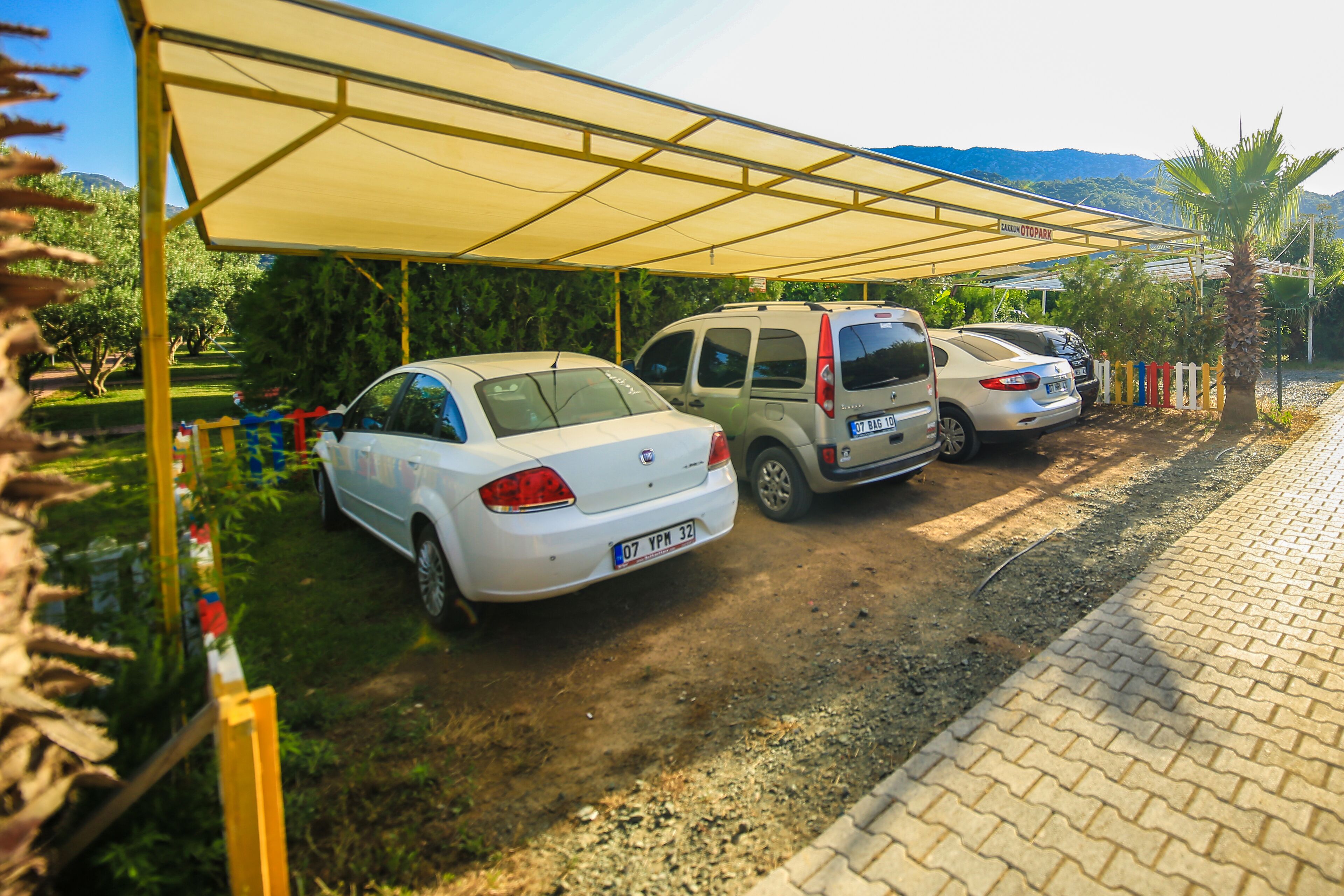 Una zona d'aparcament amb una secció coberta, un cotxe blanc i una furgoneta.