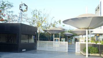 A modern building with a star-shaped sign, outdoor umbrellas, and a white fence.
