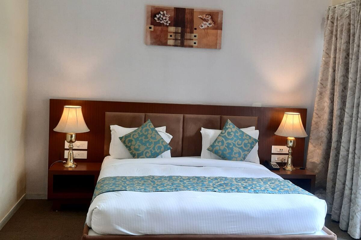 A neatly made bed with a patterned bedspread, two bedside lamps, and a small table with a magazine.