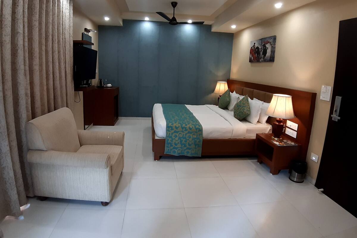 A hotel room with a bed, bedside table, lamp, and a television on a stand.