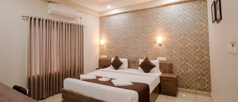 A hotel room with a large bed, bedside tables, a desk, and a ceiling fan.