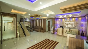 A modern reception area with a reception desk, a staircase, and a seating area. - Spring Field Billets (Kanayannur)