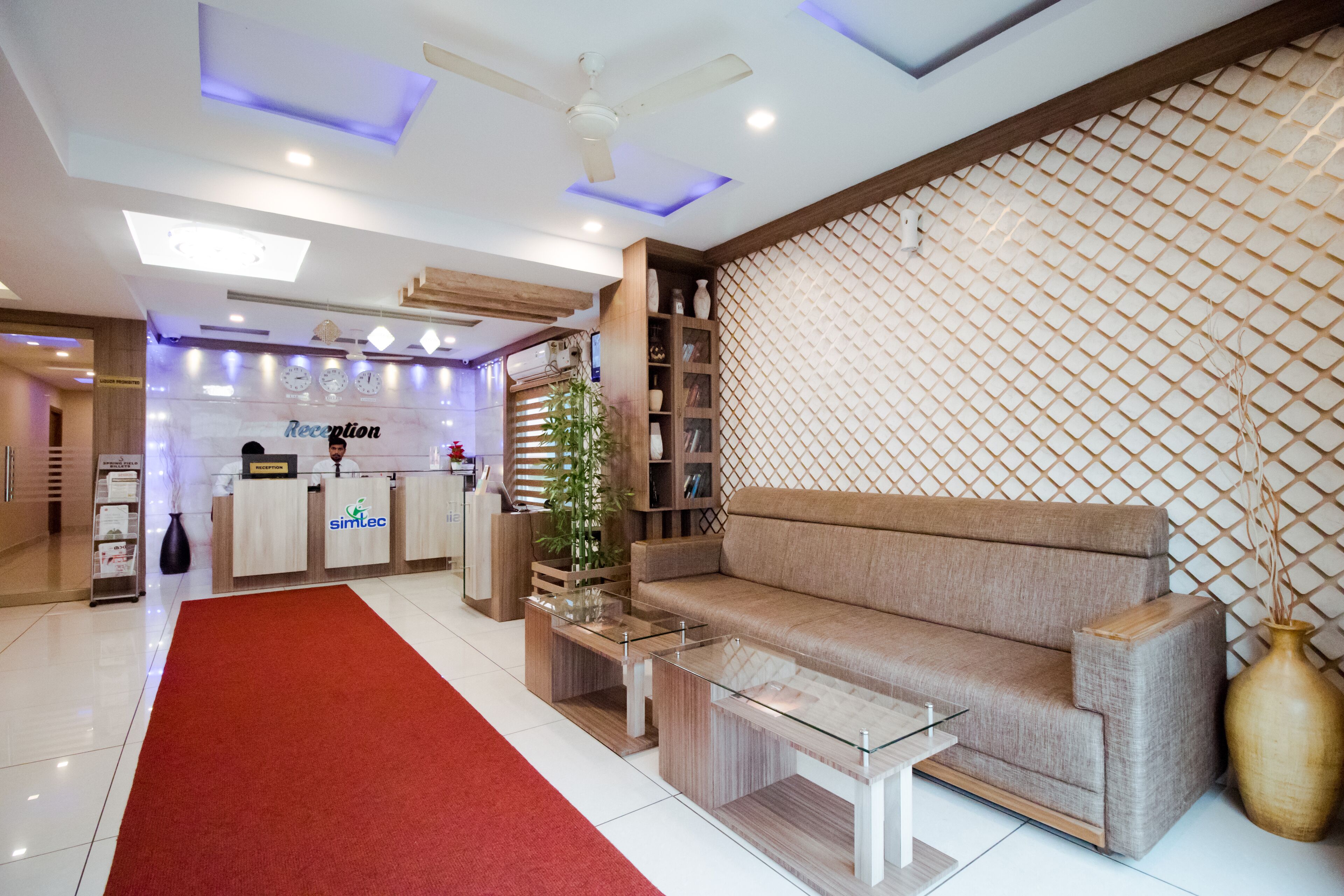 A reception area with a reception desk, a sofa, a coffee table, and a red carpet.