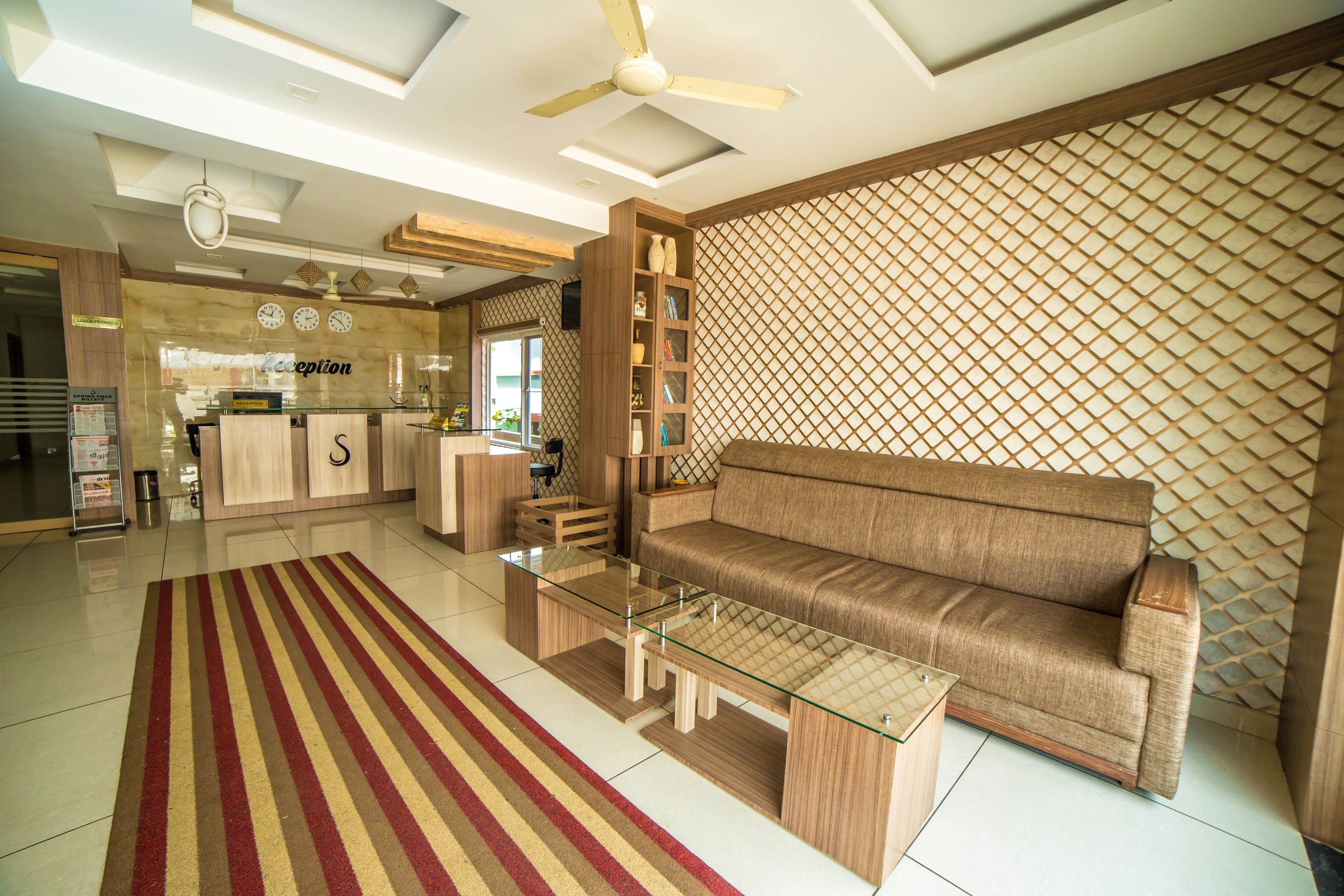 A modern living room with a sofa, glass coffee table, and a patterned rug.