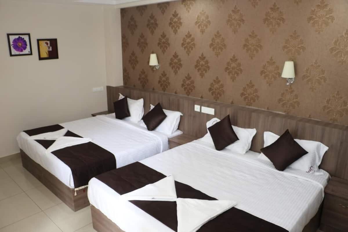 Ein Hotelzimmer mit zwei Betten, jeweils mit weißer und brauner Bettwäsche, und einer Wand mit gemustertem Tapeten.