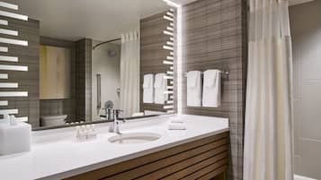 A modern bathroom with a large mirror, white sink, and wooden vanity.