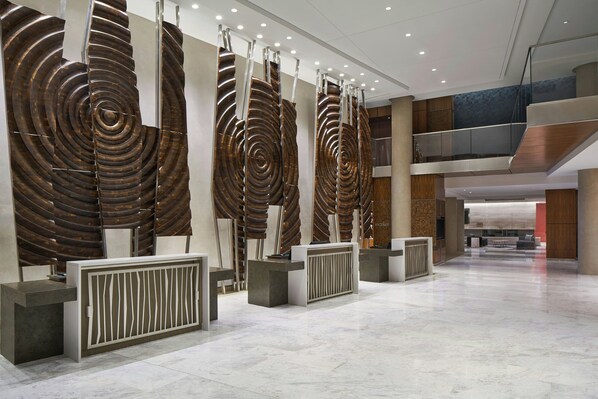 A modern lobby with a reception desk, large spiral wall art, and a spacious marble floor. - Courtyard by Marriott Washington Downtown/Convention Center (Washington)