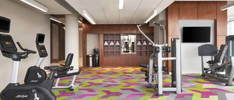 A gym with cardio machines, weightlifting equipment, and a patterned carpet.