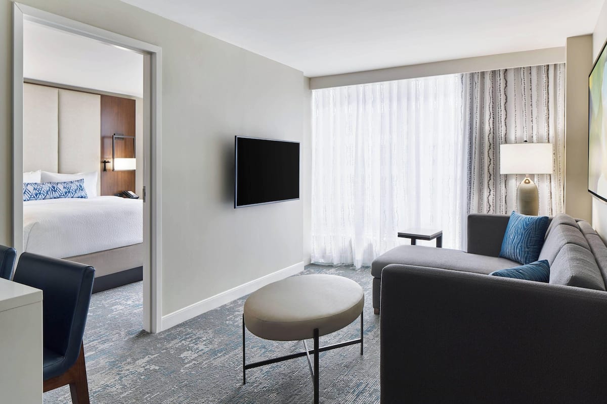 A hotel room with a bed, a TV, a sofa, and a small table.