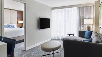 Et hotelværelse med seng, fjernsyn, sofa og et lille bord.
