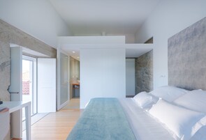 Un dormitorio moderno con una cama grande, un banco y vistas al baño.