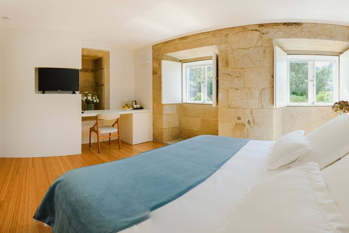 A bedroom with a bed, a desk, and a television.