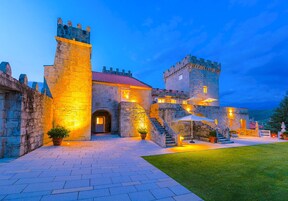 Un castillo de piedra histórico con un patio central, una gran puerta de entrada y una escalera que conduce a los niveles superiores.