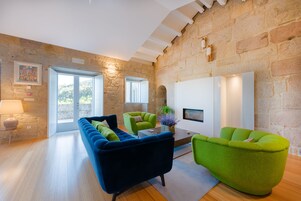 Una sala de estar moderna con una pared de piedra, un sofá azul, sillones verdes y una chimenea.