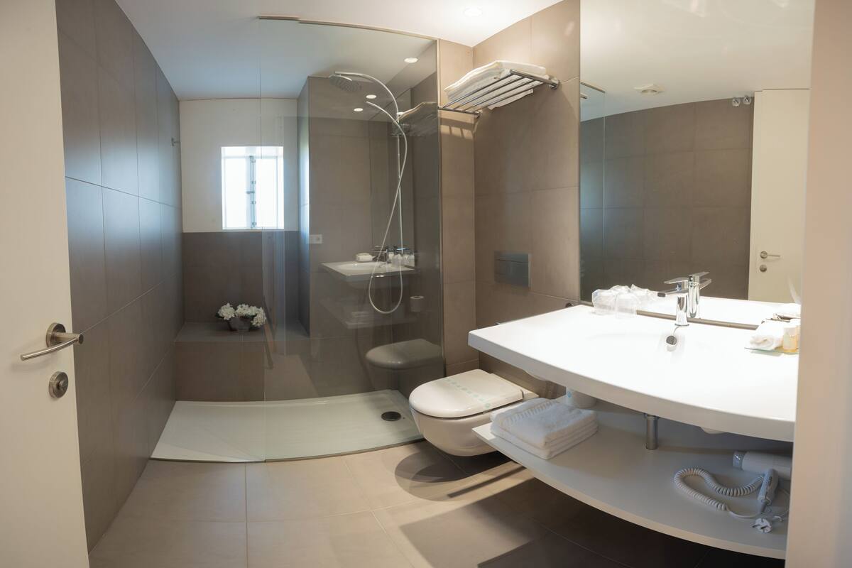 A modern bathroom with a glass-enclosed shower, a toilet, and a vanity with a sink and mirror.