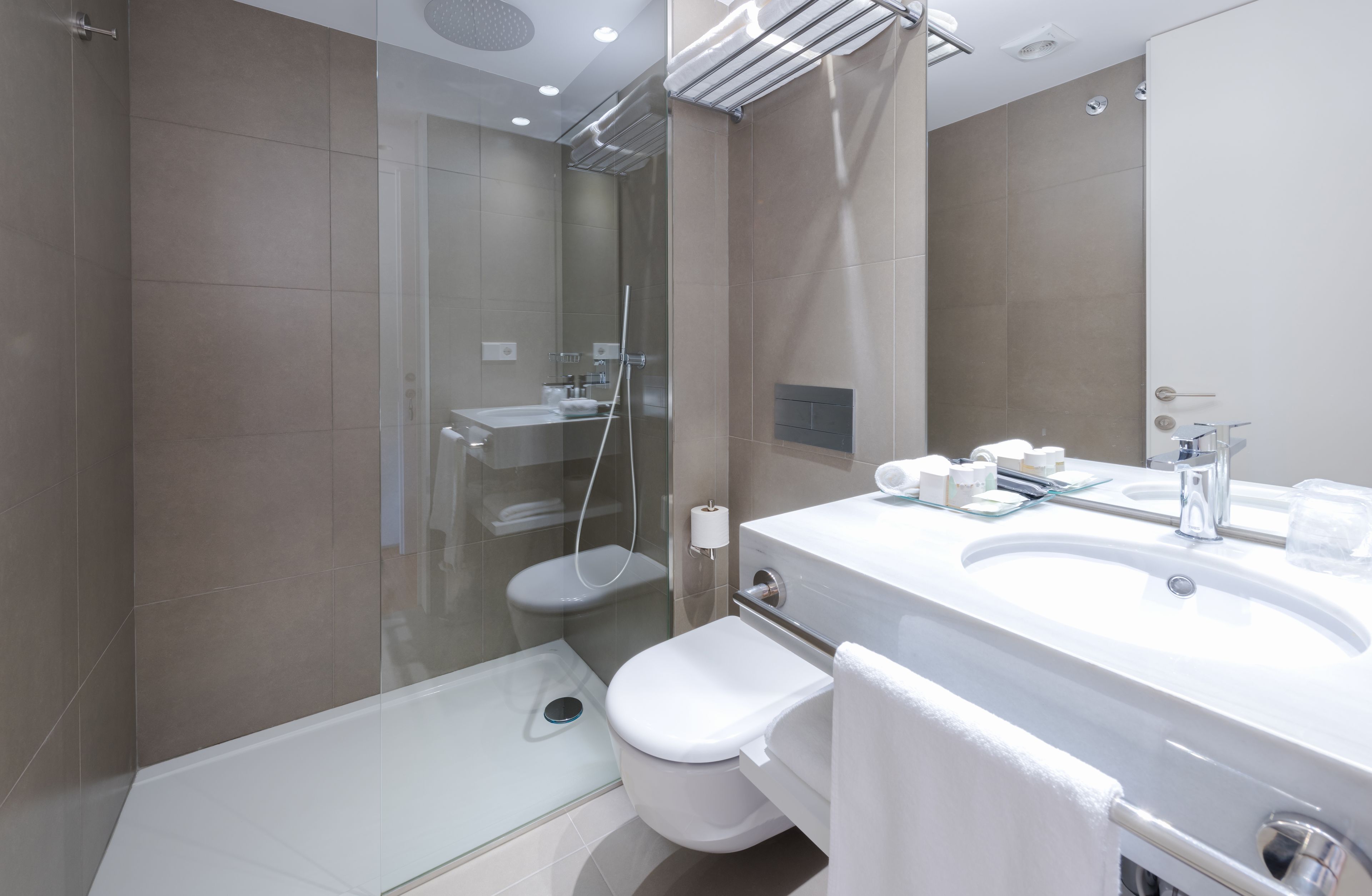 A modern bathroom with a glass-enclosed shower, a white toilet, and a large sink with a mirror.