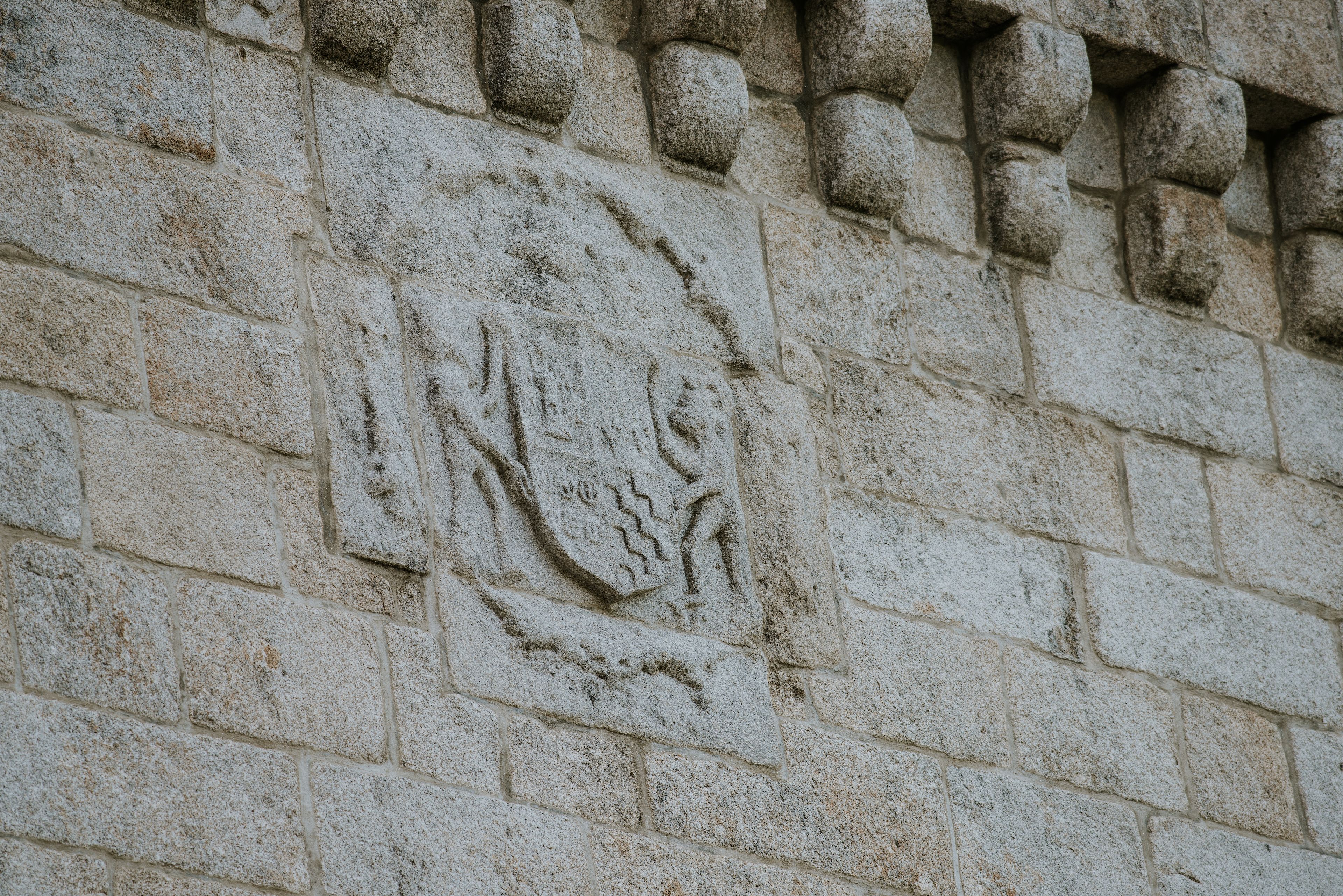 Un mur de pierre orné d’un blason sculpté.