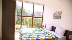 Un dormitorio con una cama grande, una ventana y vistas a la vegetación.