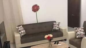 Una sala de estar con un sofá, dos sillones, una mesa de centro y un jarrón de flores.