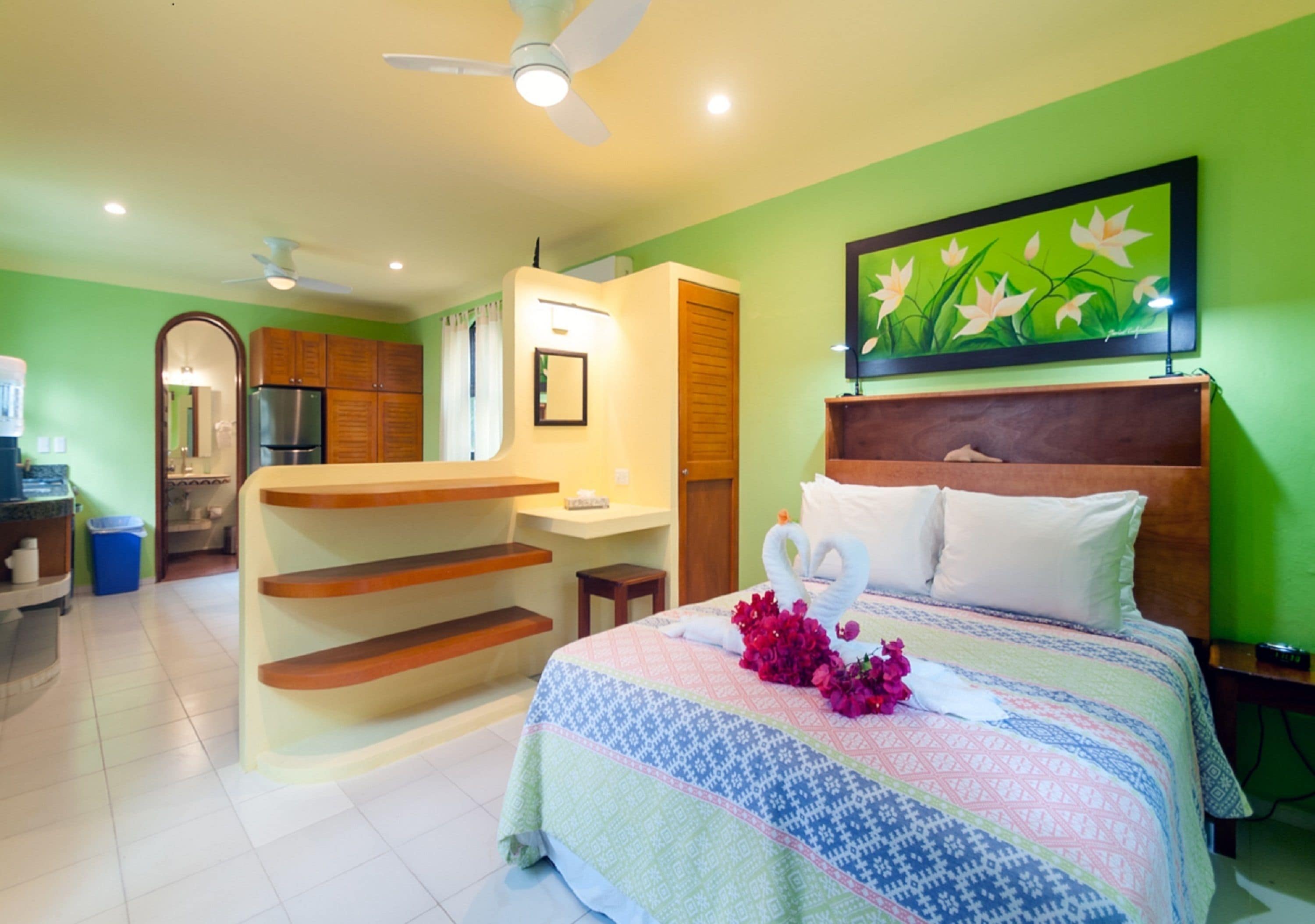 A hotel room with a bed, a desk, and a kitchenette.