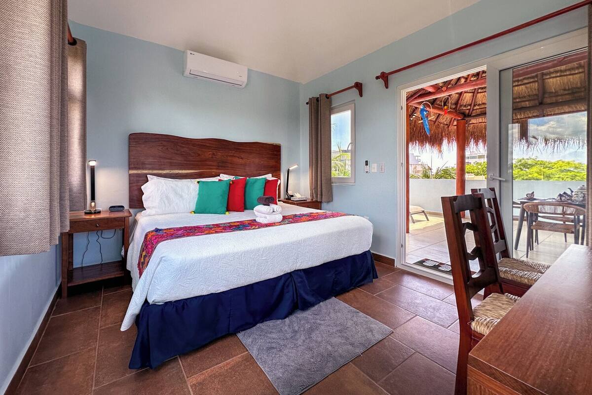 A bedroom with a bed, nightstands, a window, and a view of the outside.