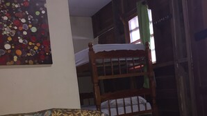 Una habitación con una cama, un edredón estampado con motivos florales, una litera de madera y una pared decorada con un cuadro abstracto y colorido.