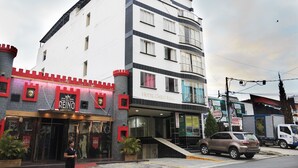 Un hotel con fachada temática de castillo, una escalera que conduce a la entrada y un SUV estacionado.