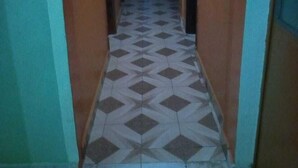 Un pasillo estrecho con suelo de baldosas estampadas y paredes de madera.