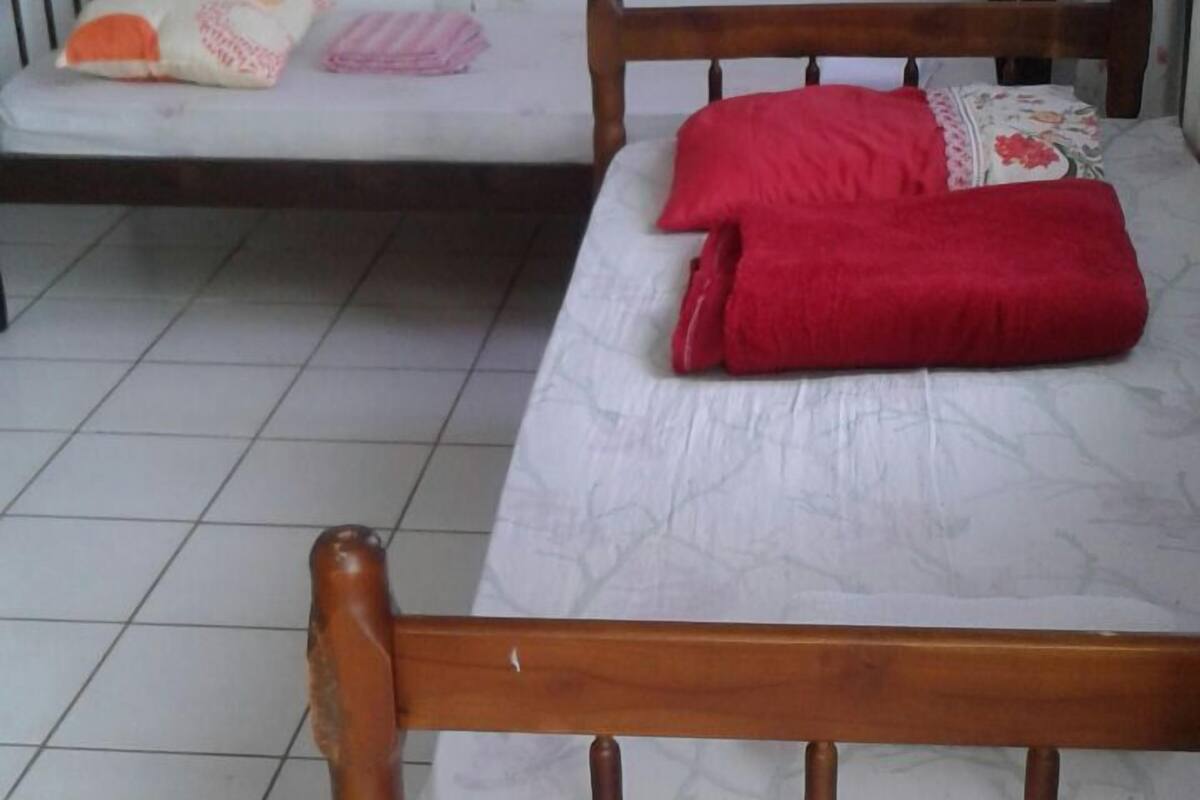 A bedroom with two beds, one with a wooden frame and the other with a metal frame.