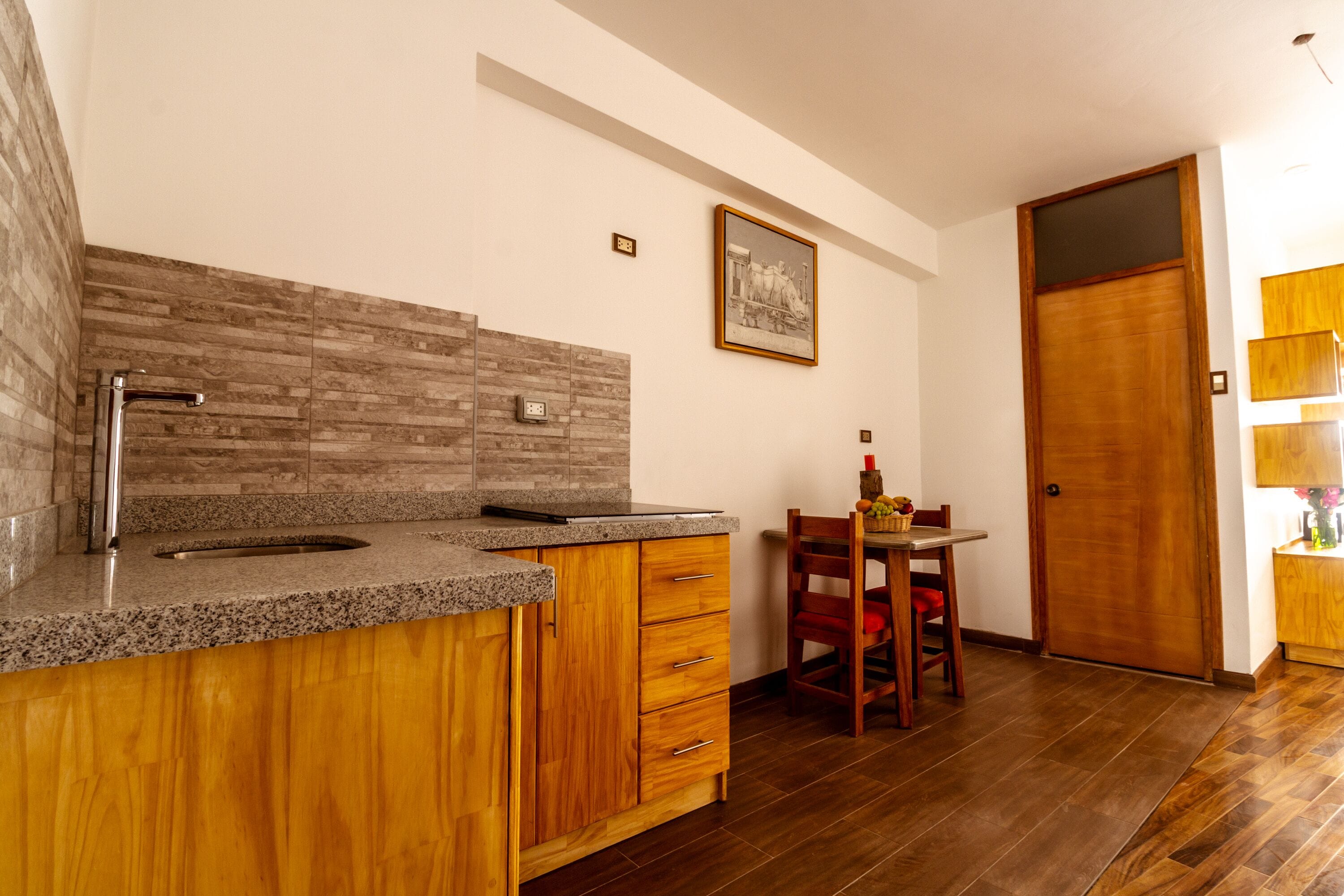 Una cocina moderna con encimeras de granito, armarios de madera y un lavamanos empotrado.